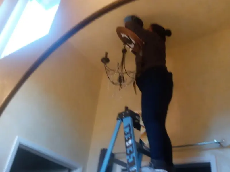 Electrician installing a chandelier in a Dundee residence